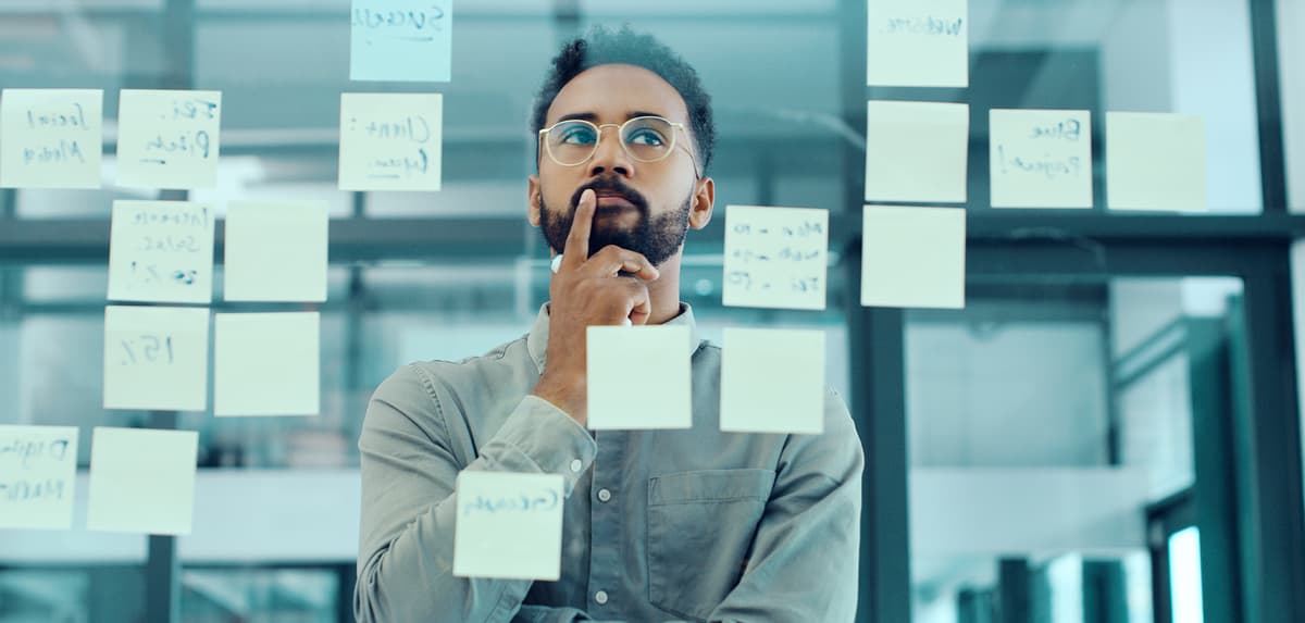Person thinking with sticky notes on glass